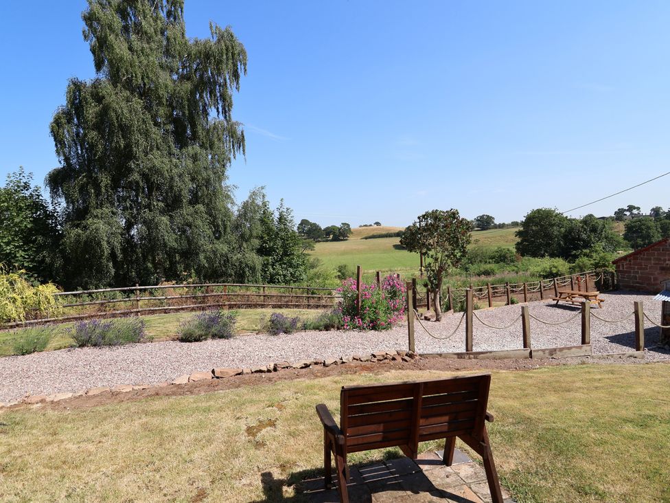 A garden view with a bench and flowers at 1 Fountain Cottages in Peckforton, Tarporley