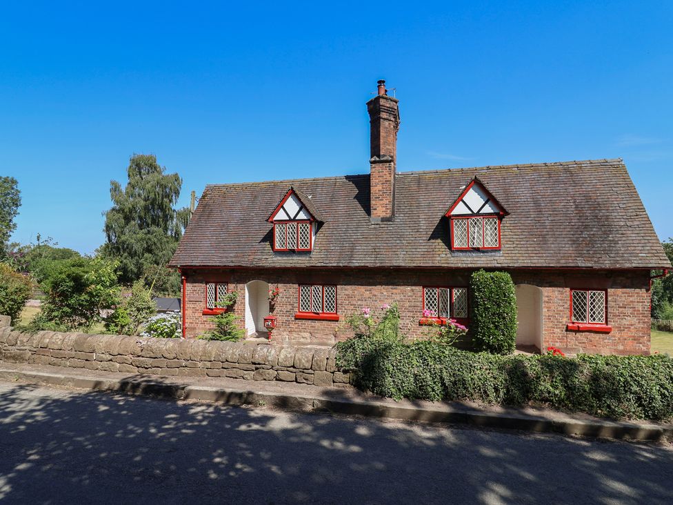 A cottage with a chimney and flower bed at 1 Fountain Cottages in Peckforton, Tarporley