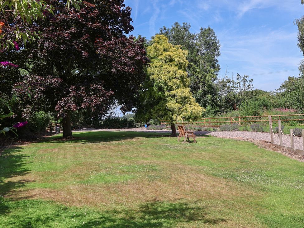 A garden with trees and a pathway at 1 Fountain Cottages, Peckforton, Tarporley