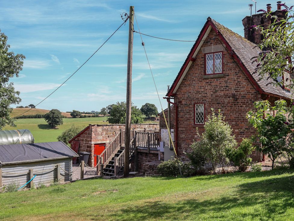 An outdoor view of a house with stairs and a shed at 1 Fountain Cottages in Peckforton, Tarporley