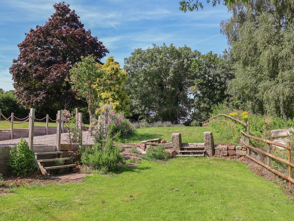 A garden with trees and a gravel path at 1 Fountain Cottages, Peckforton, Tarporley