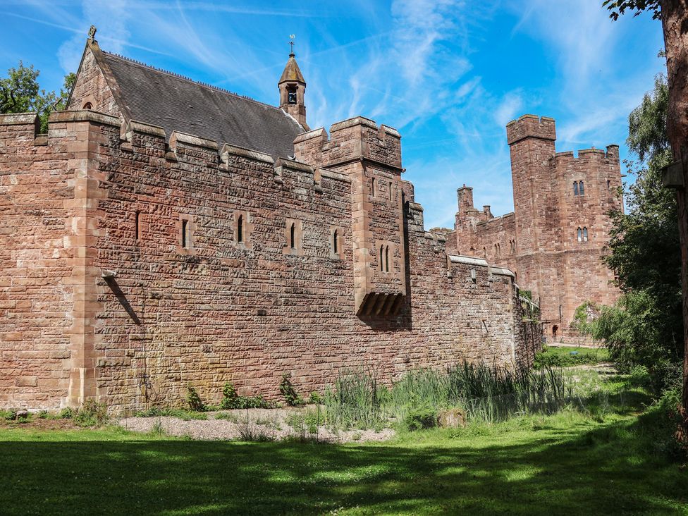 A castle wall with a watchtower and greenery at 1 Fountain Cottages in Peckforton, Tarporley