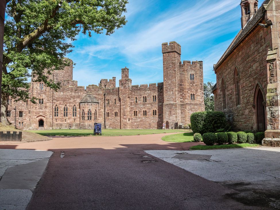 A castle with towers and greenery at 1 Fountain Cottages in Peckforton, Tarporley
