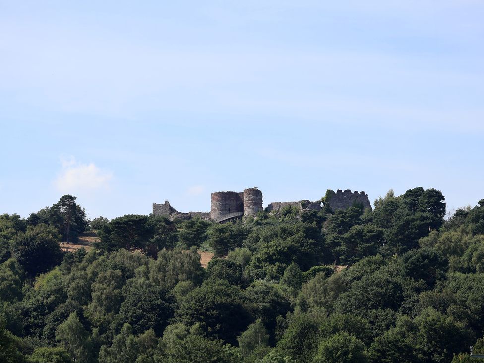 A castle ruins on a hill surrounded by trees at 1 Fountain Cottages in Peckforton, Tarporley