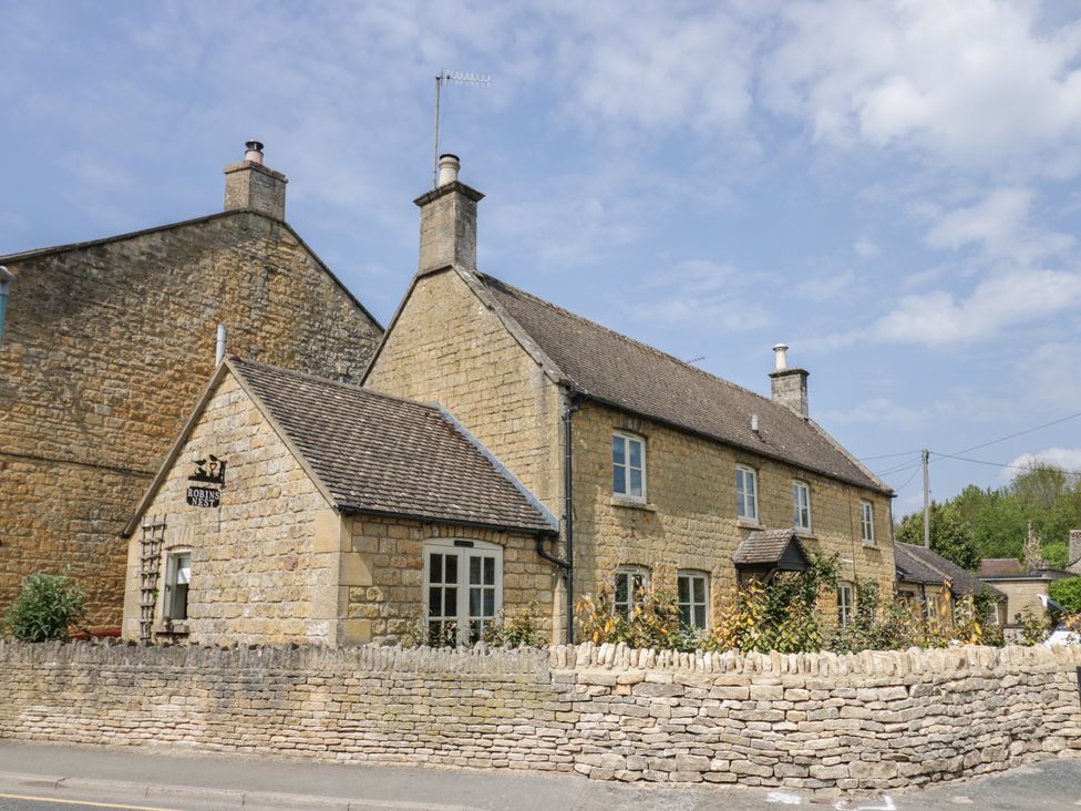 A stone house with a wall and a sign at Robins Nest in Bourton-On-The-Water
