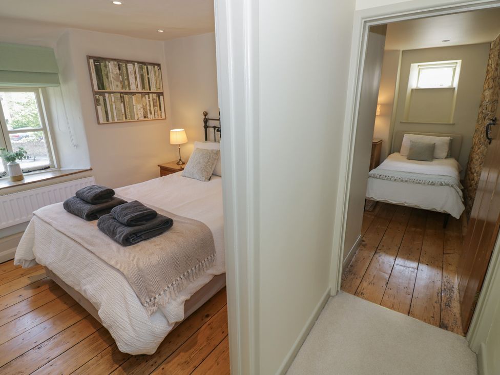 A bedroom with a bed, lamp, and towels at Robins Nest in Bourton-On-The-Water