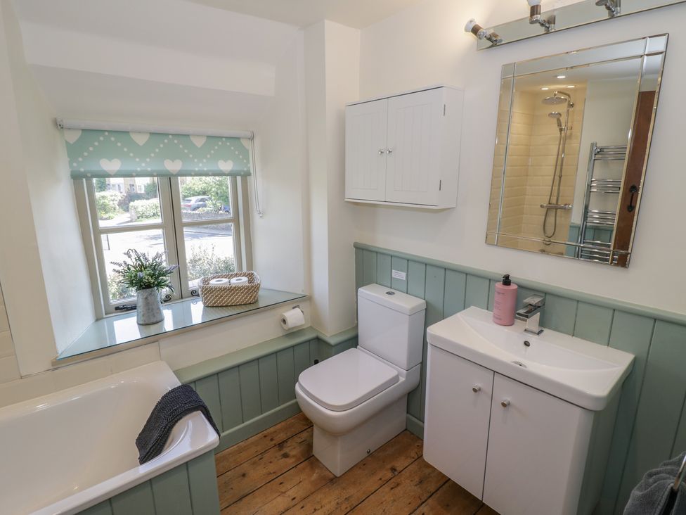 A bathroom with a bath tub, toilet, and sink at Robins Nest in Bourton-On-The-Water