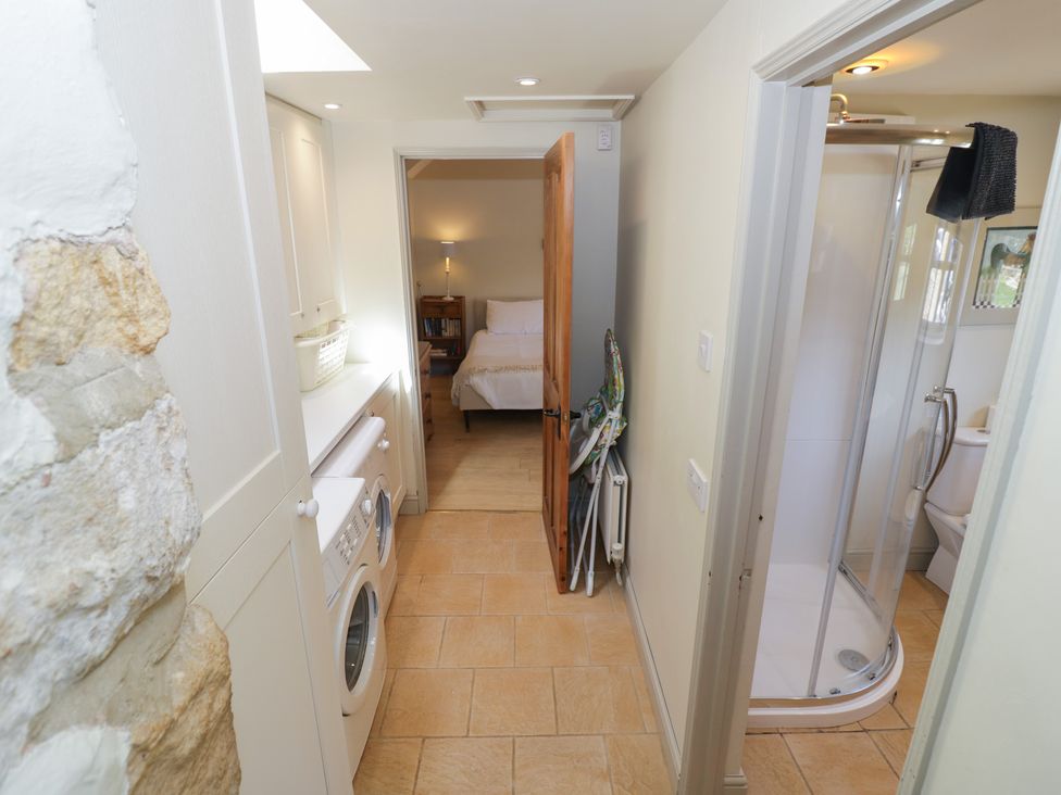 A hallway with a washing machine and doors to a bed and a bathroom at Robins Nest in Bourton-On-The-Water