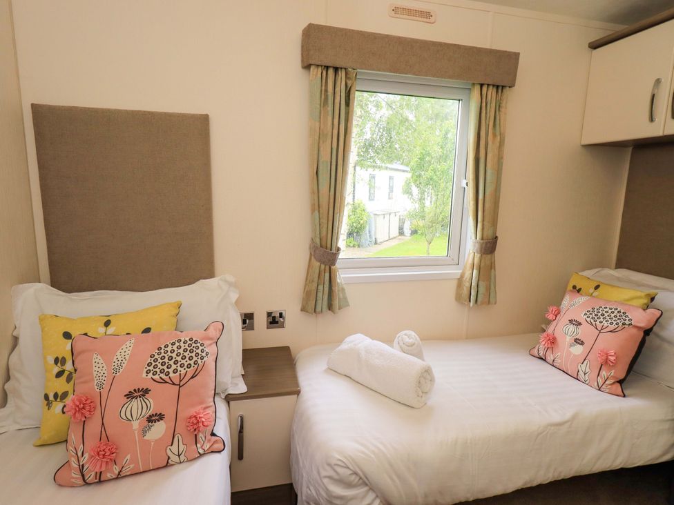 A bedroom with two beds and a window at 41, Grandma's Cottage, South Lakeland Leisure Village near Carnforth