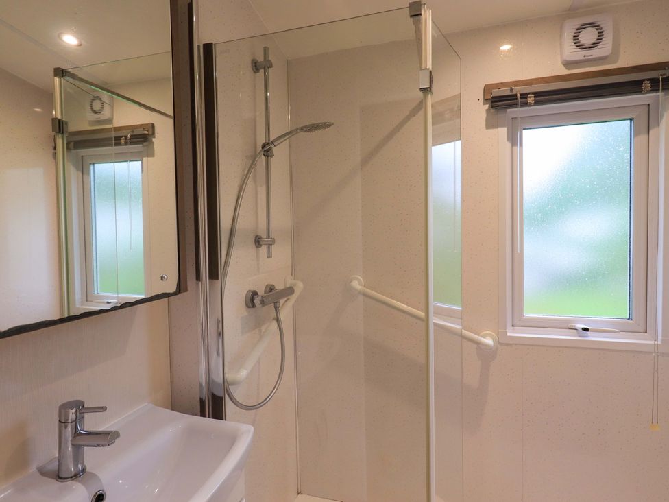 A bathroom with a shower, sink, and window at 41, Grandma's Cottage South Lakeland Leisure Village near Carnforth