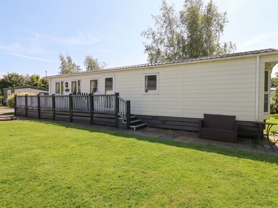 A mobile home with a deck and lawn at 41, Grandma's Cottage South Lakeland Leisure Village near Carnforth
