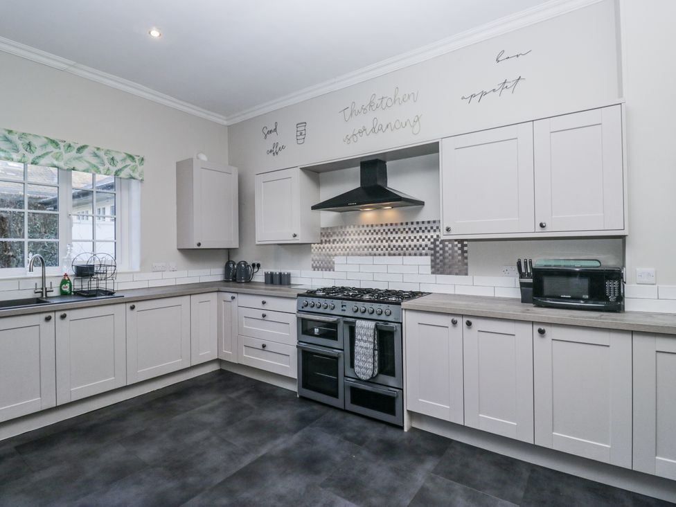 A kitchen with cabinets, sink, oven and microwave at Clarence House Dalton-In-Furness
