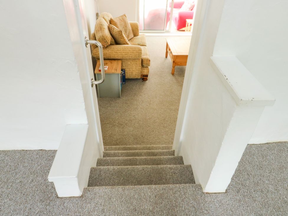 Stairs leading to a living room with a couch and coffee table at Pen Bonc Llanddaniel Near Gaerwen