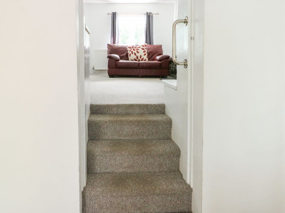 A view of stairs leading to a living room with a sofa at Pen Bonc in Llanddaniel Near Gaerwen