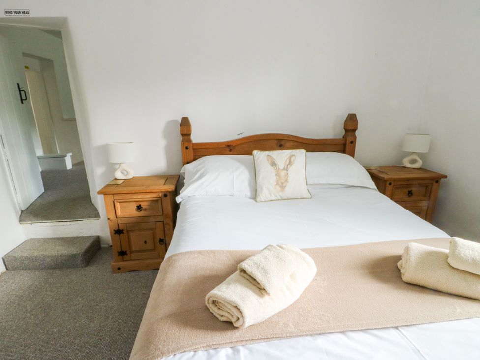 A bedroom with a bed and nightstands at Pen Bonc Llanddaniel Near Gaerwen