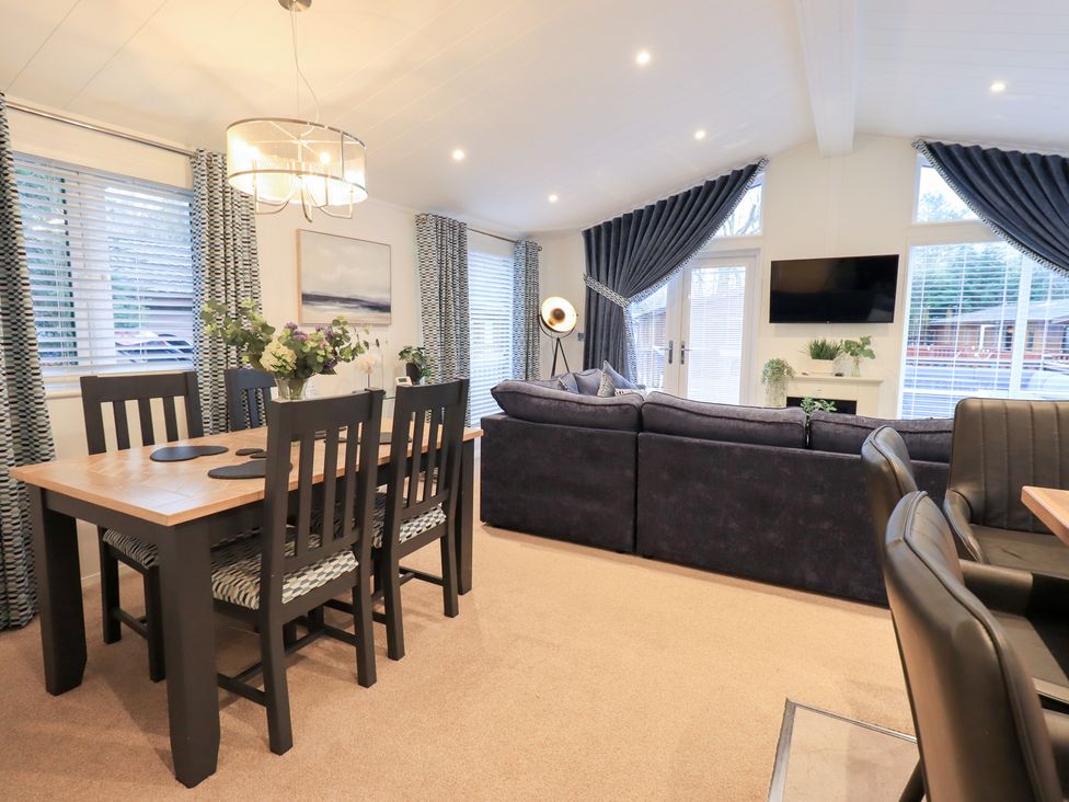 A living room with a sofa and dining area at Unique Luxury Lodge, 1 Langdale, White Cross Bay near Windermere