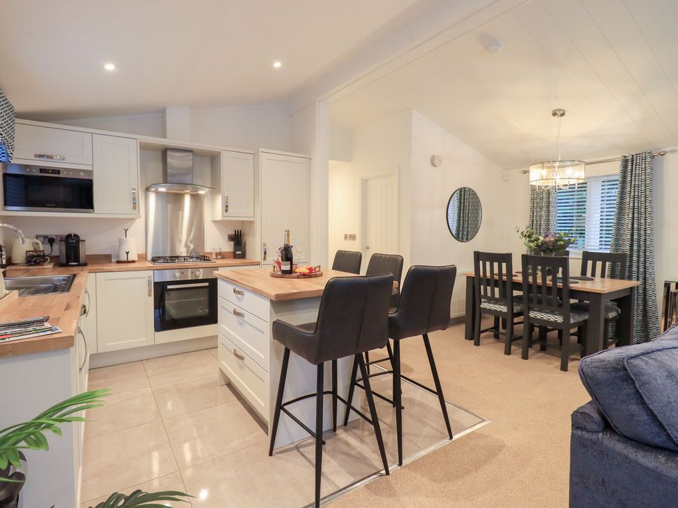 A kitchen with bar stools and dining table at Unique Luxury Lodge 1 Langdale, White Cross Bay near Windermere