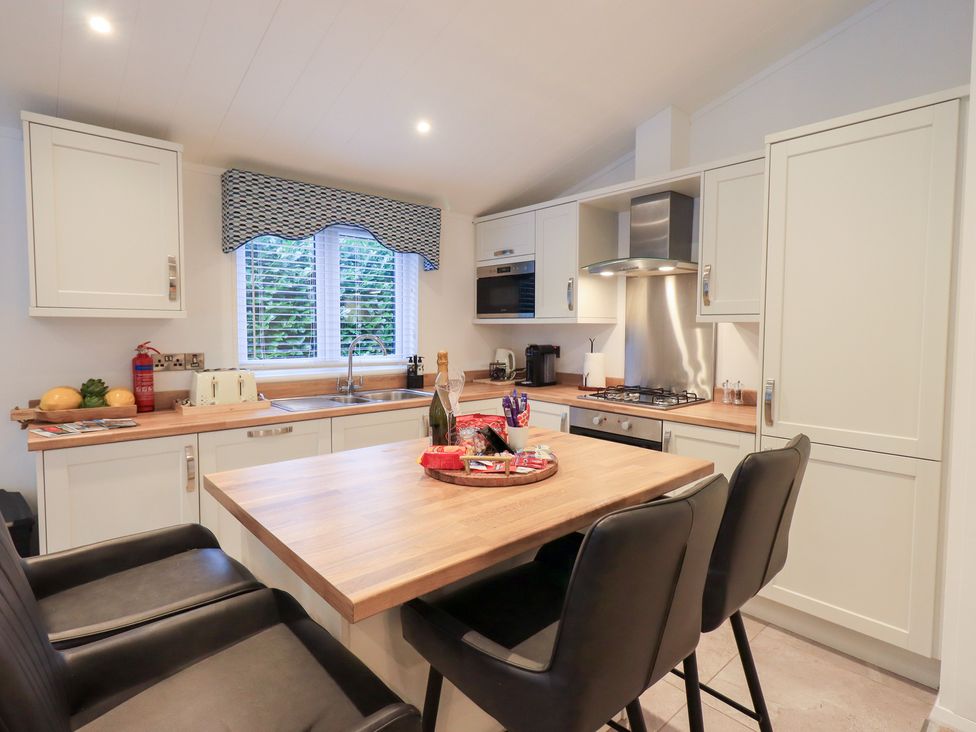 A kitchen with a wooden countertop and black bar stools at Unique Luxury Lodge, 1 Langdale, White Cross Bay near Windermere