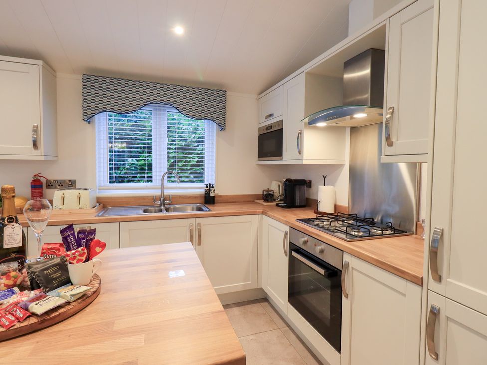 A kitchen with a sink, oven, and cabinets at Unique Luxury Lodge, 1 Langdale, White Cross Bay near Windermere