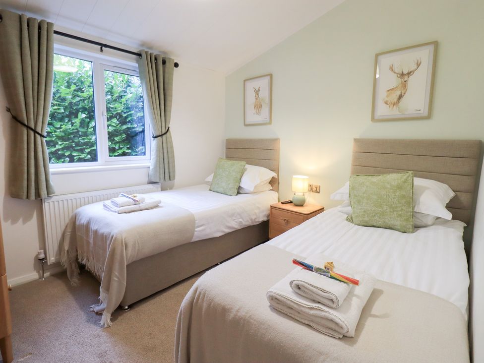 A bedroom with twin beds and a bedside table at Unique Luxury Lodge 1 Langdale, White Cross Bay near Windermere