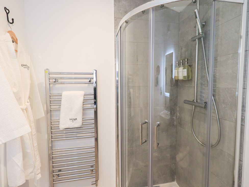A shower with glass doors and a towel rack at Unique Luxury Lodge, 1 Langdale, White Cross Bay near Windermere