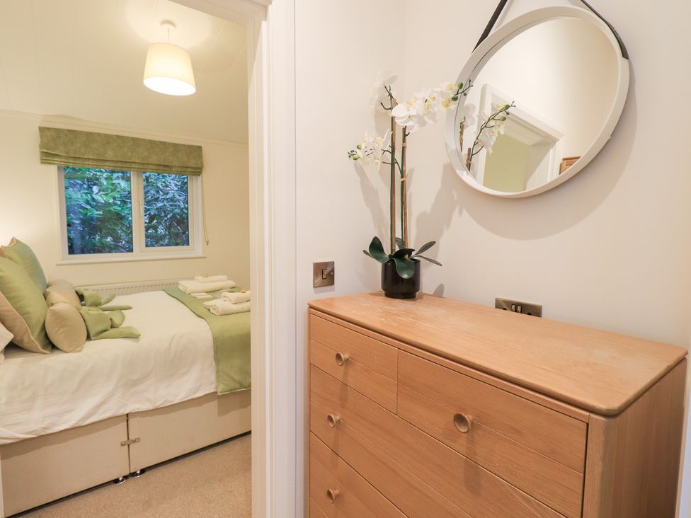 A bedroom with a bed and dresser at Unique Luxury Lodge, 1 Langdale, White Cross Bay near Windermere