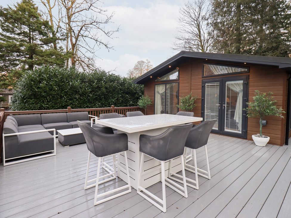 An outdoor deck with seating and a dining table at Unique Luxury Lodge, 1 Langdale, White Cross Bay near Windermere