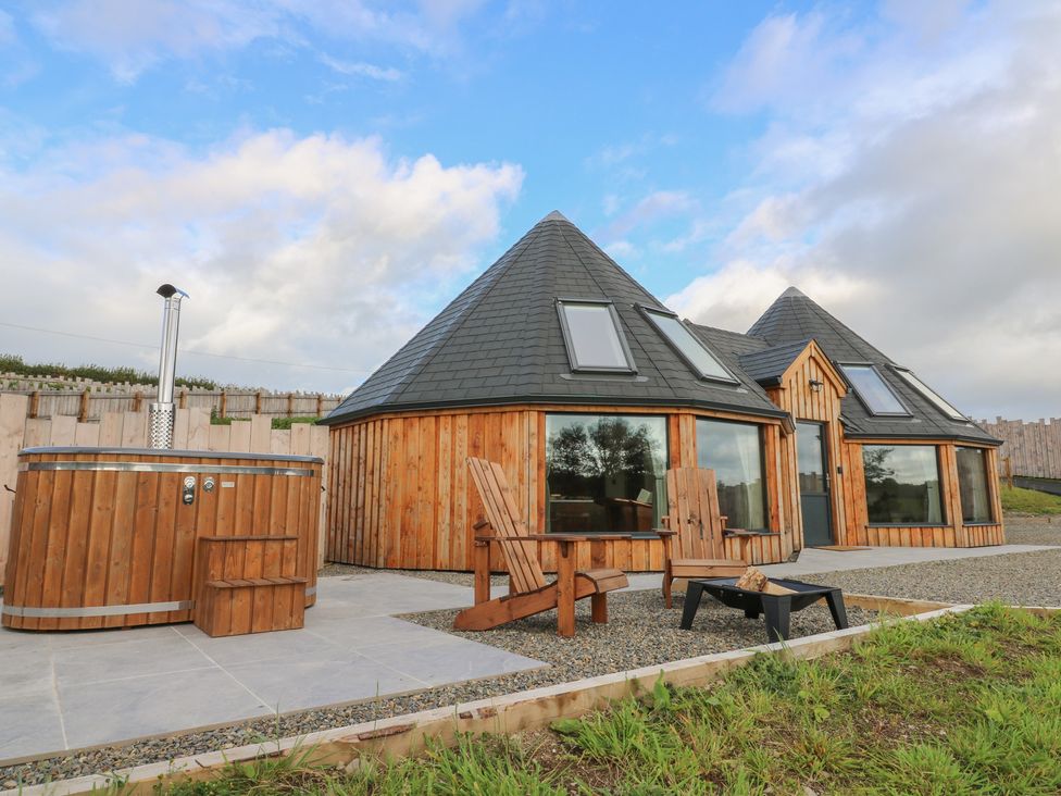 An outdoor area with a hot tub and wooden chairs at Ty Crwn in Lampeter