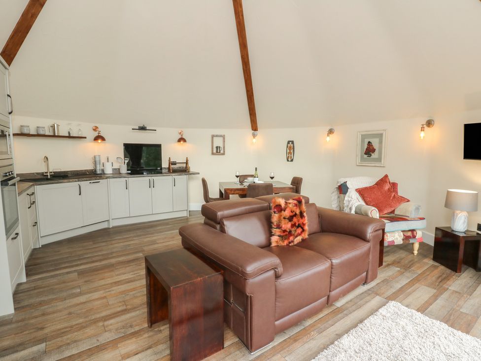 A living room with a sofa, coffee table, and kitchen area at Ty Crwn in Lampeter