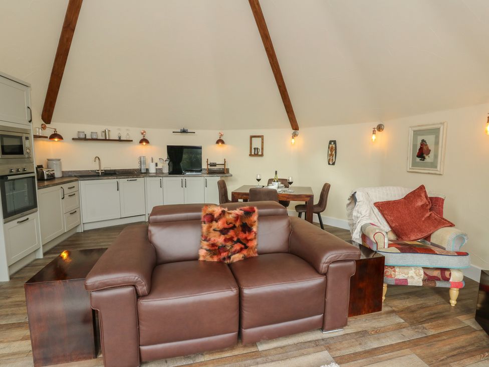A living room with a sofa and dining area at Ty Crwn in Lampeter