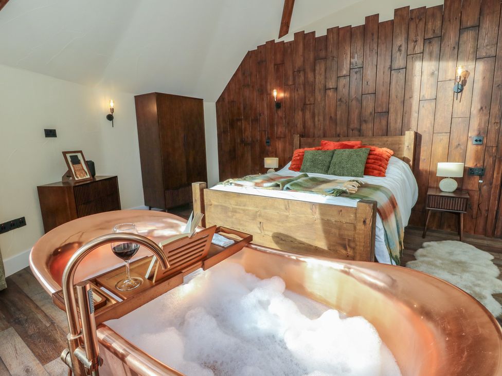 A bedroom with a bathtub and a bed at Ty Crwn in Lampeter