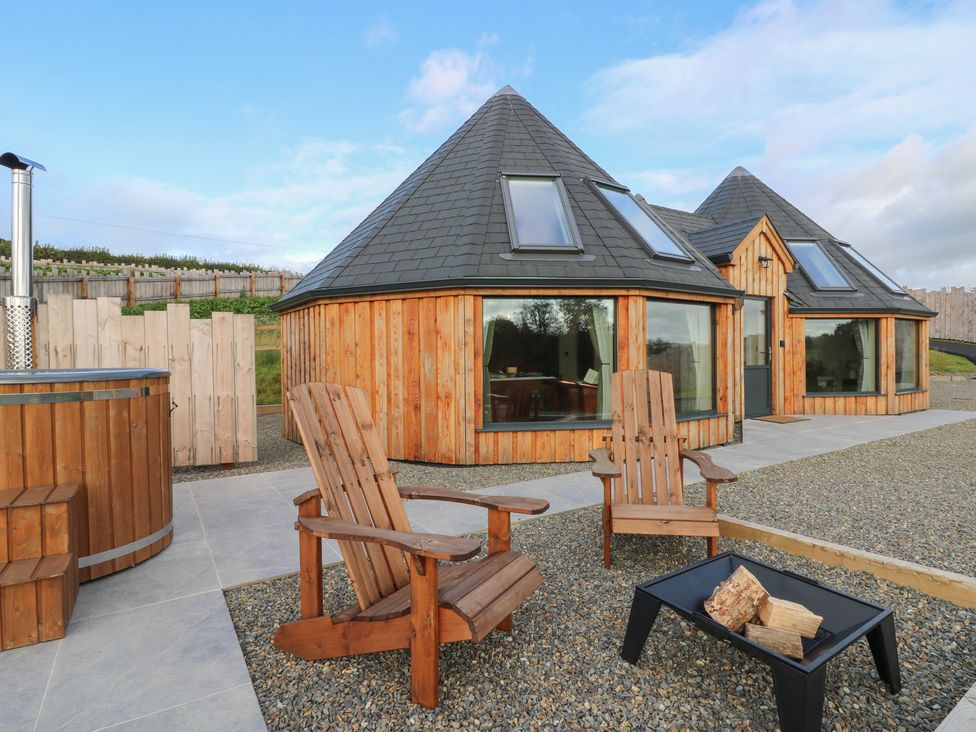 An outdoor seating area with wooden chairs and a hot tub at Ty Crwn in Lampeter