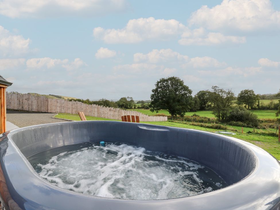 A hot tub with water and trees in the background at Ty Crwn in Lampeter