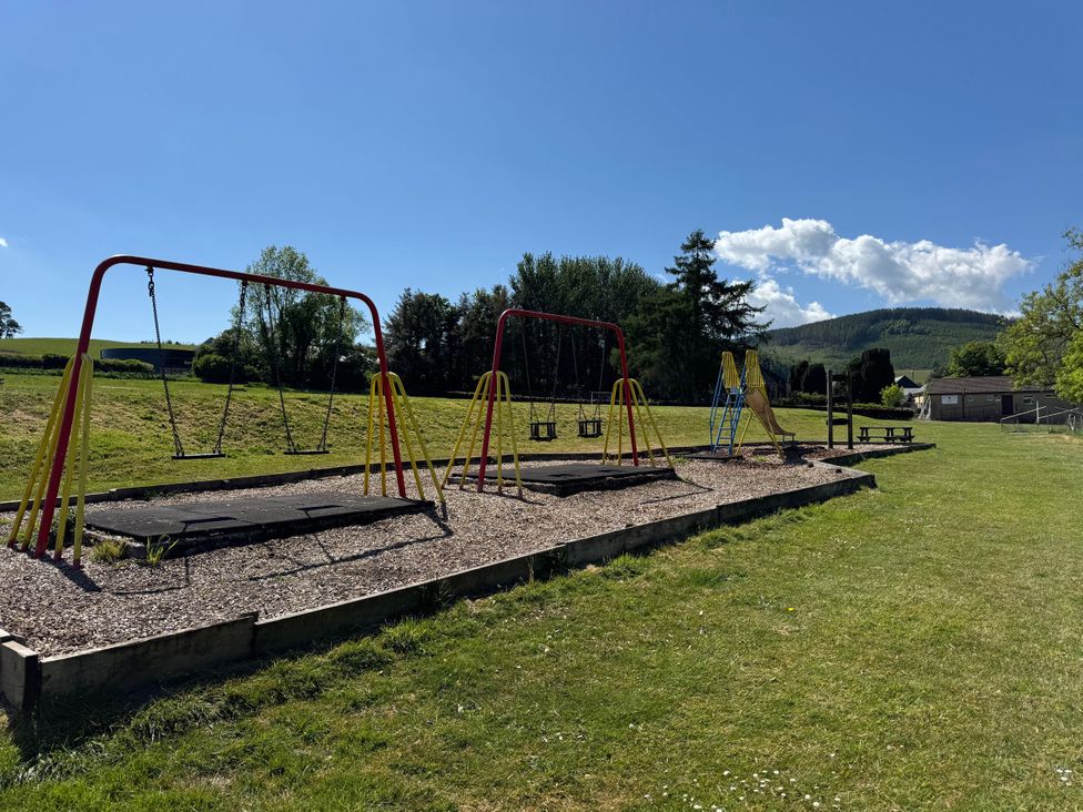 An outdoor playground with swings and a slide at The Steading in Terregles near Dumfries