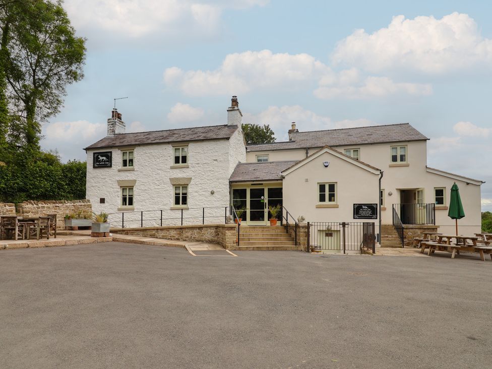 A pub building with a front entrance and outdoor seating at Upstairs at the White Lion 