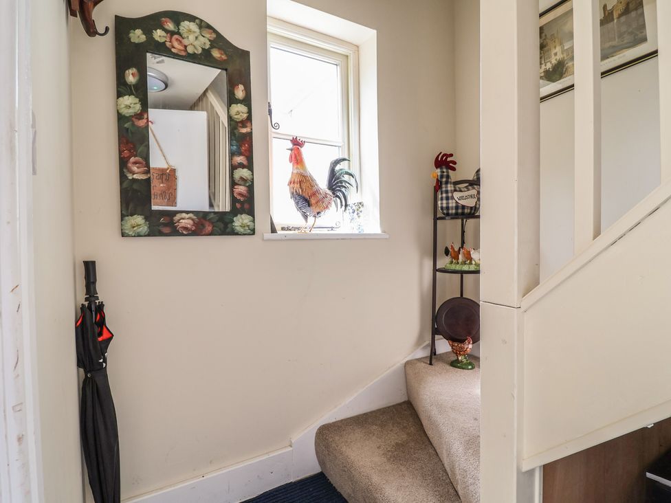 A hallway with a mirror, window, rooster figurine and stairs at Upstairs at the White Lion
