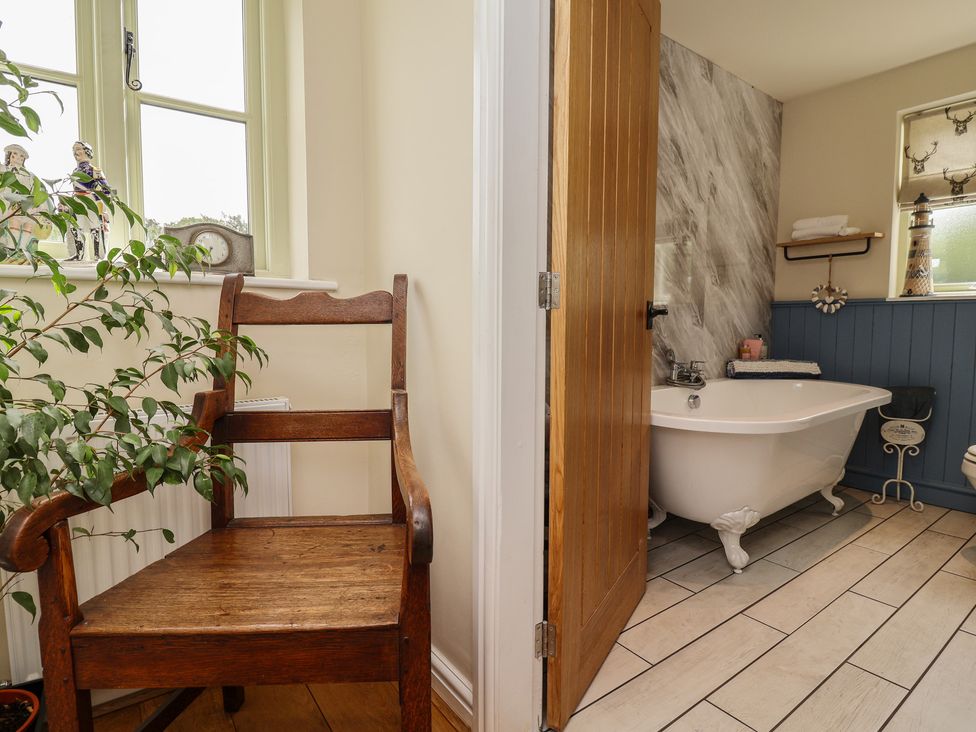 A bathroom with a bathtubs and a wooden chair at Upstairs at the White Lion