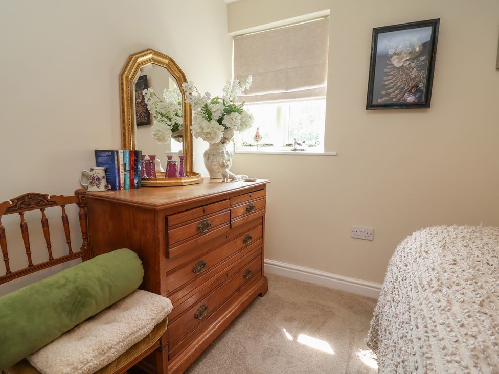 A bedroom with a dresser and flowers on the window at Upstairs at the White Lion