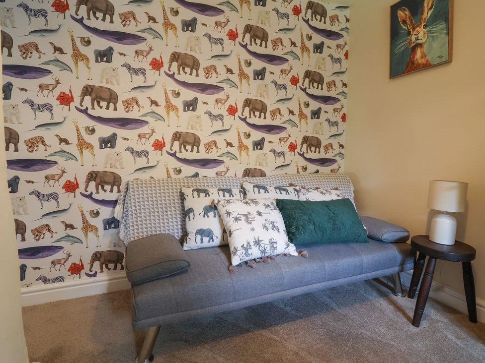 A snug with a sofa and animal-themed wallpaper at Upstairs at the White Lion