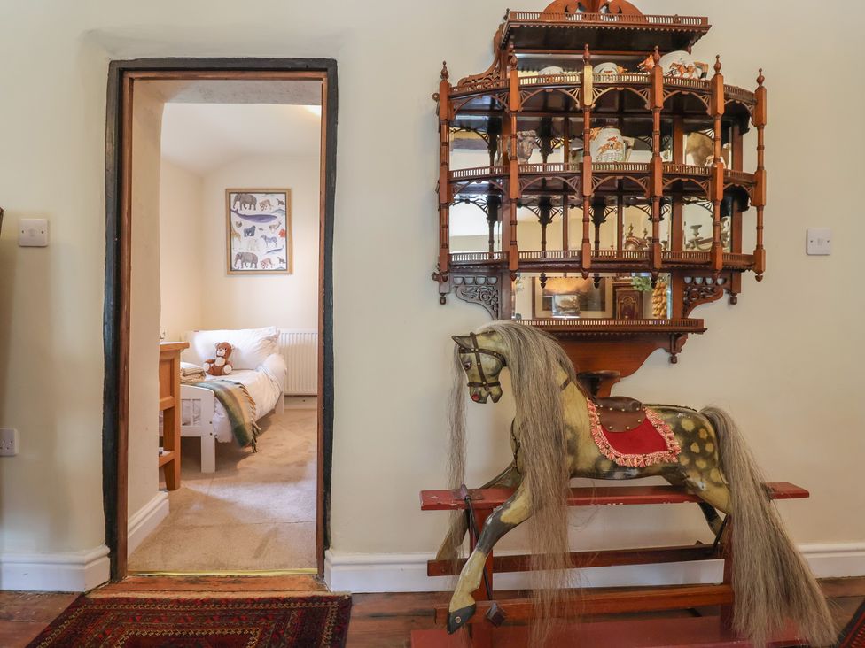 A hallway with a rocking horse and a doorway to a bedroom at Upstairs at the White Lion 