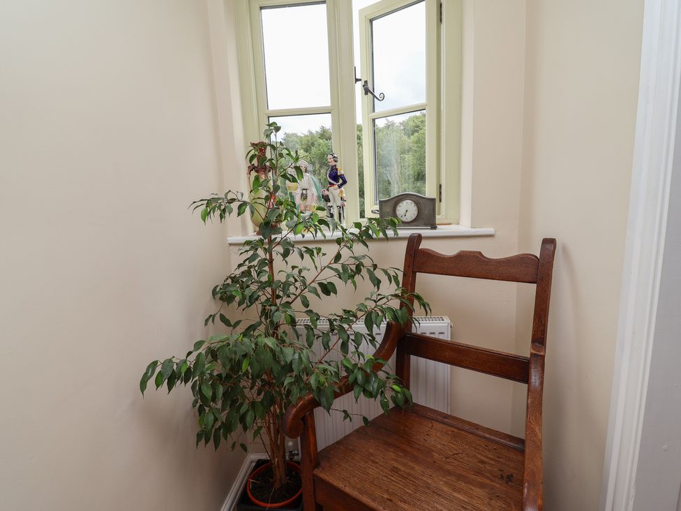 A hallway with a chair, plant, clock and window at Upstairs at the White Lion