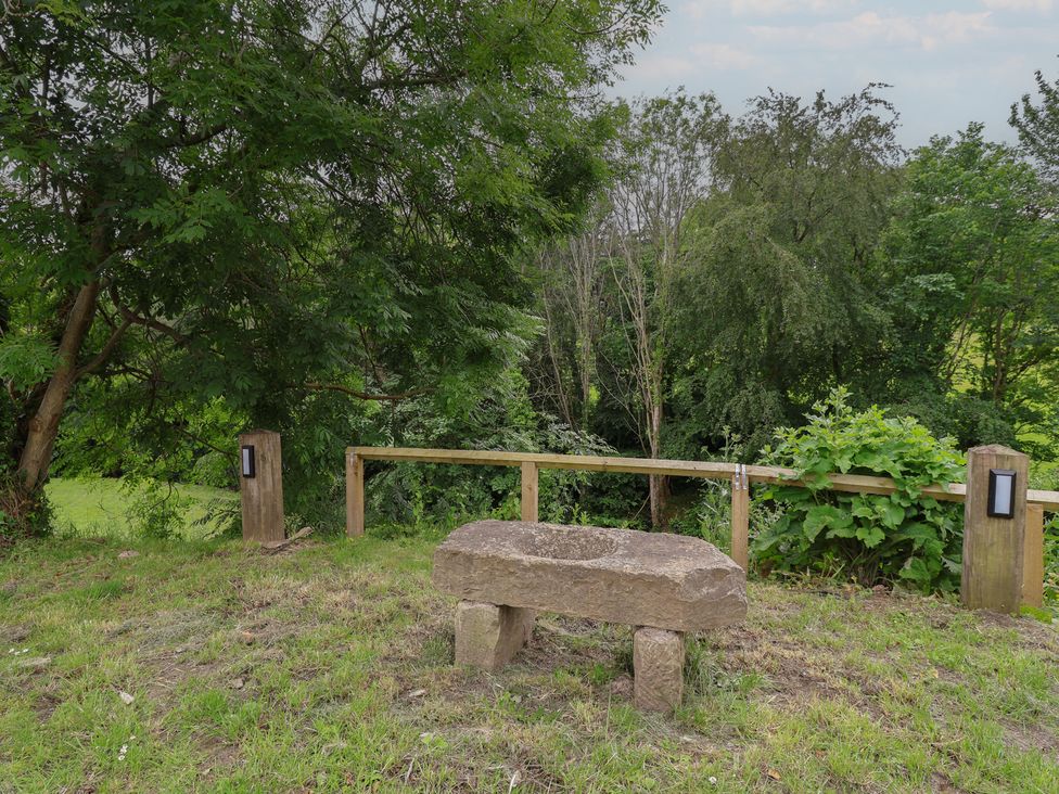 A stone bench with wooden railing and trees at Upstairs at the White Lion