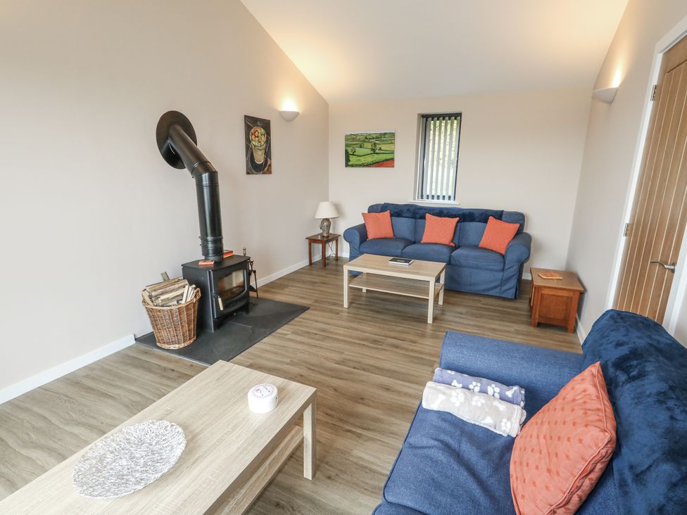 A living room with a sofa and wood stove at Frogwell in Yetminster