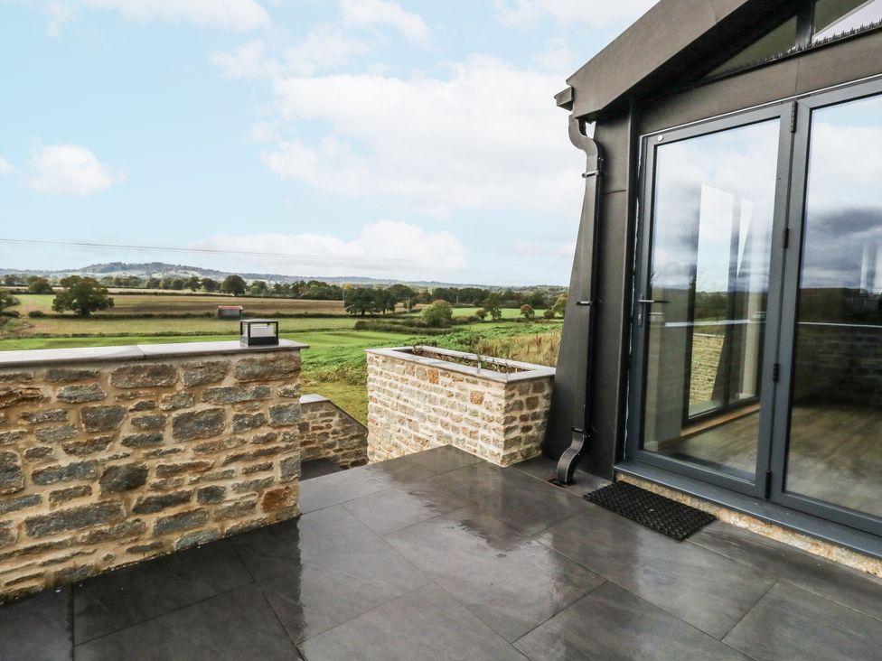 An outdoor area with a stone wall and sliding glass door at Frogwell in Yetminster