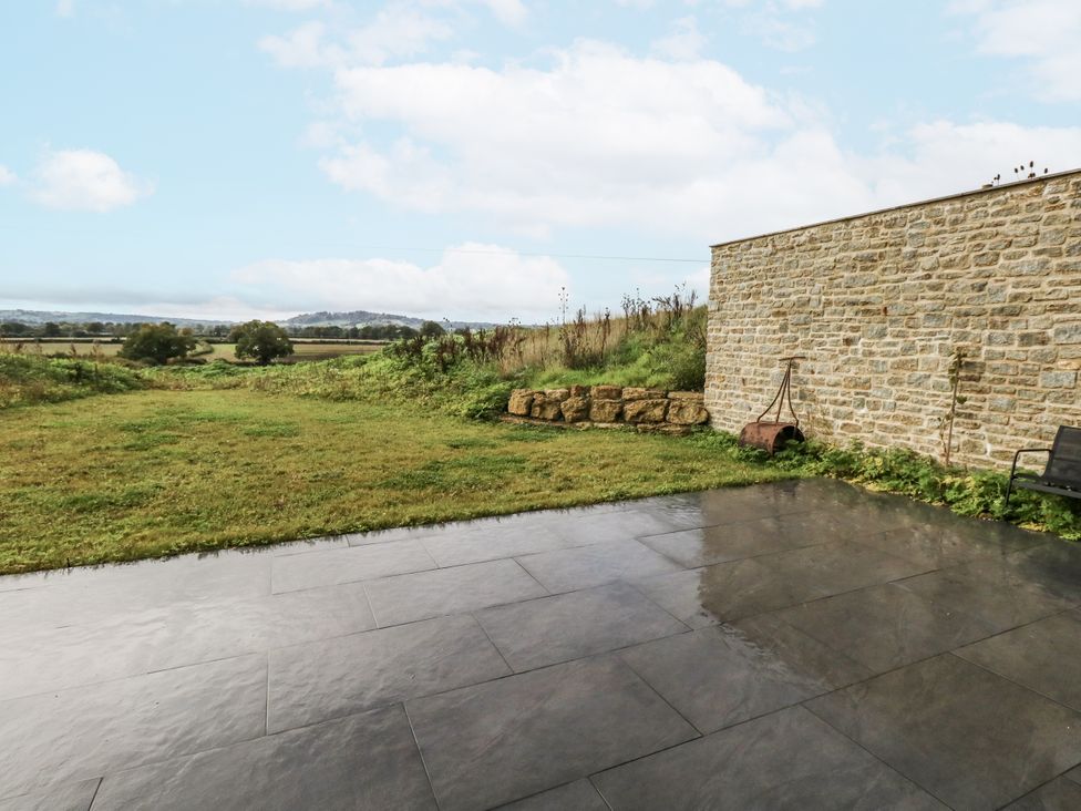 A garden area with a stone wall and patio at Frogwell in Yetminster