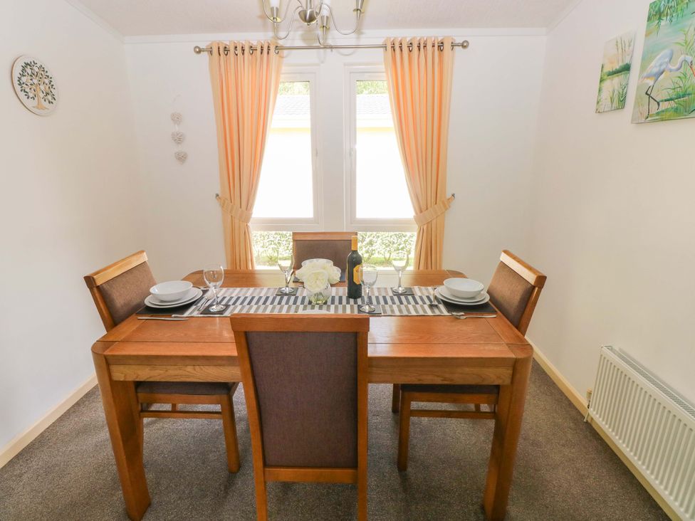 A dining room with a wooden table and chairs at Serenity in Kilgetty