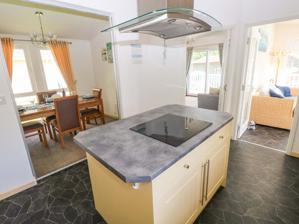 A kitchen with an island and dining area at Serenity in Kilgetty