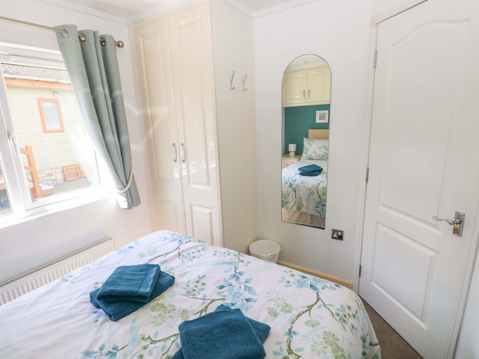 A bedroom with a bed and wardrobe at Serenity in Kilgetty