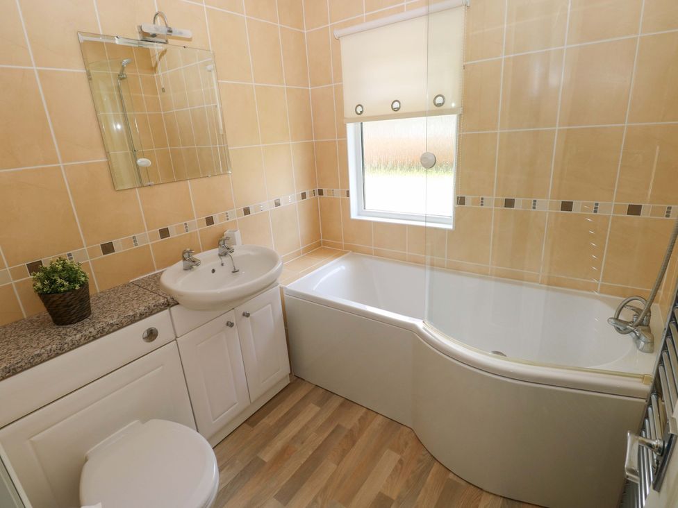 A bathroom with a bath, sink, and toilet at Serenity in Kilgetty