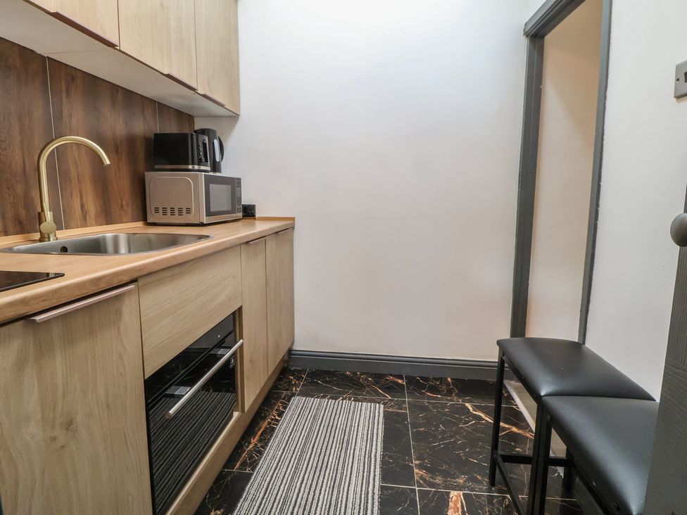 A kitchen with a sink, microwave and stools at The Cloud Apartment 1 Chester